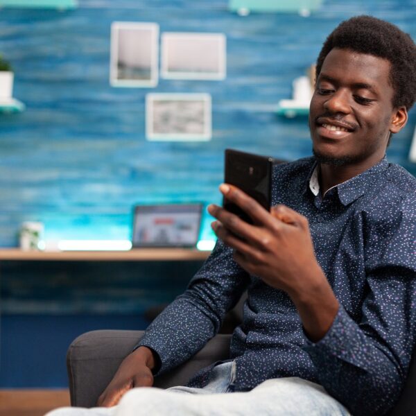 Black man greeting colleagues on video call conference in living room. Working from home african american remote worker in distance communication chat, learning about business project